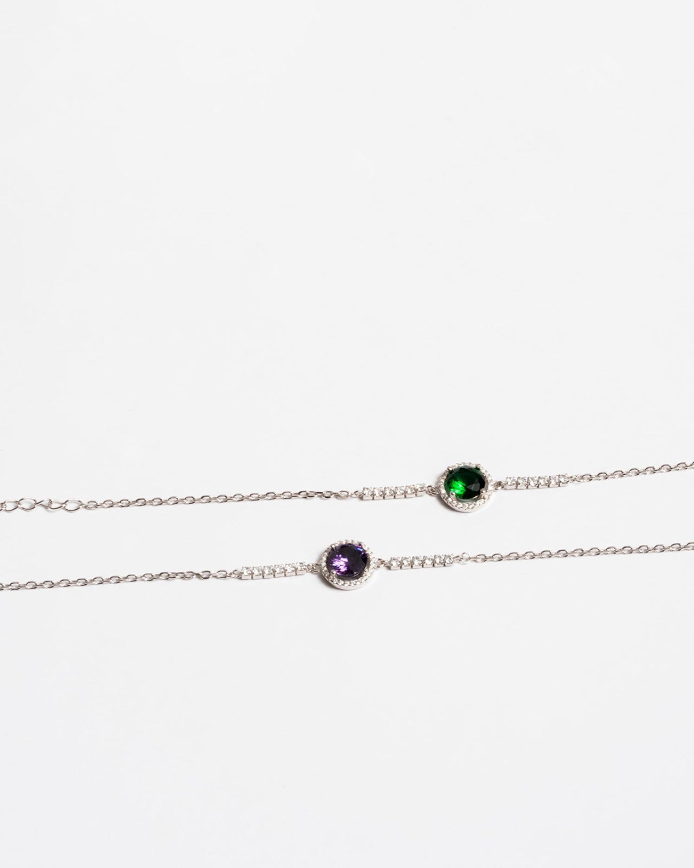 Elegant 925 silver bracelet with green gemstone and the other a purple gemstone, adorned with delicate cubic zirconia , showcasing minimalist and modern design .