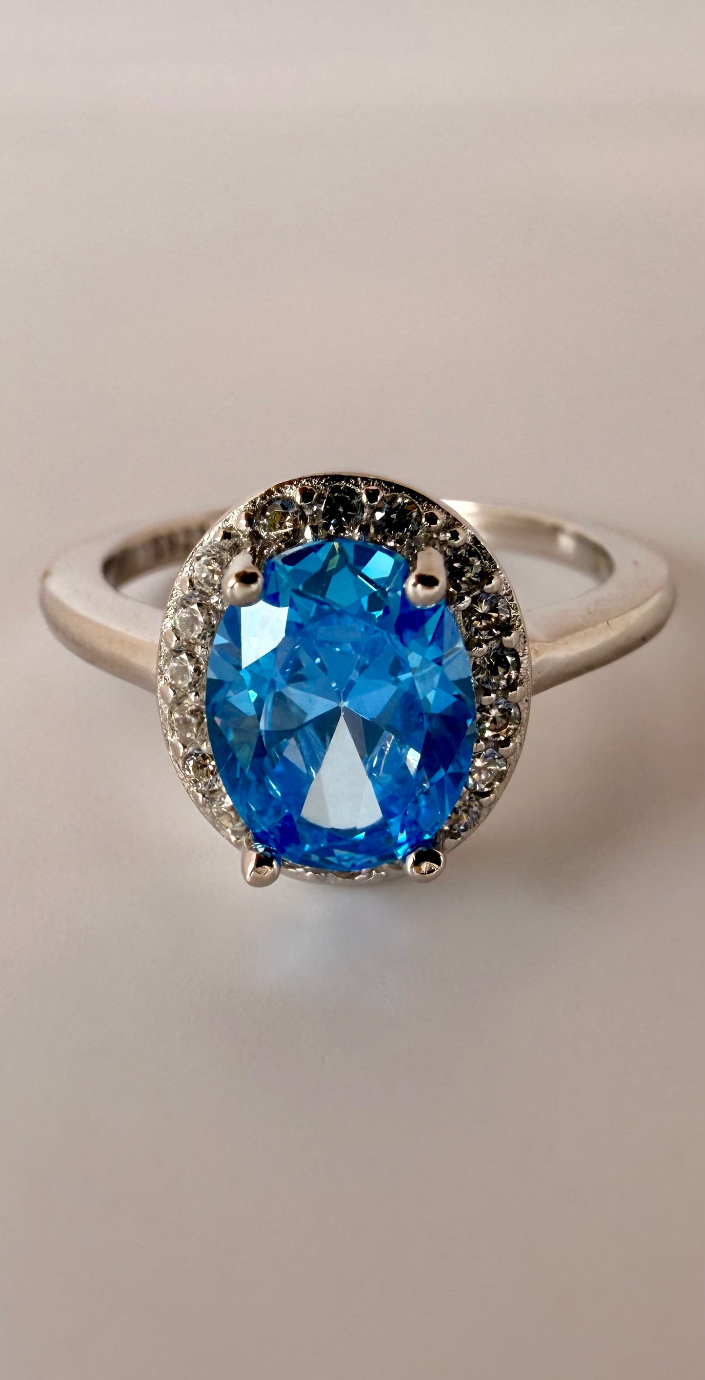 elegant sterling silver ring featuring a vibrant blue cushion-cut gemstone and clear halo accents by eclat gioielli