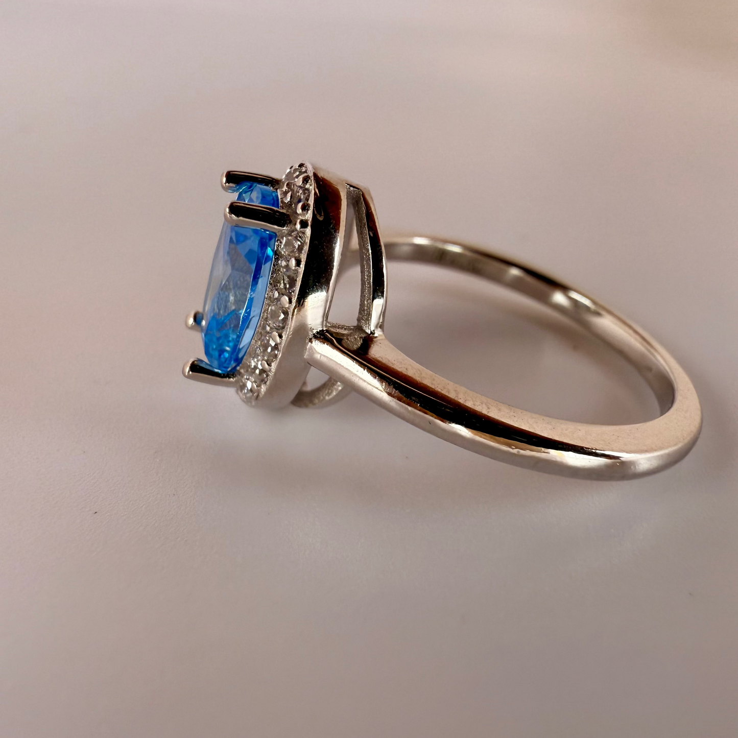 sterling silver ring with cushion-cut blue gemstone and clear halo accents
