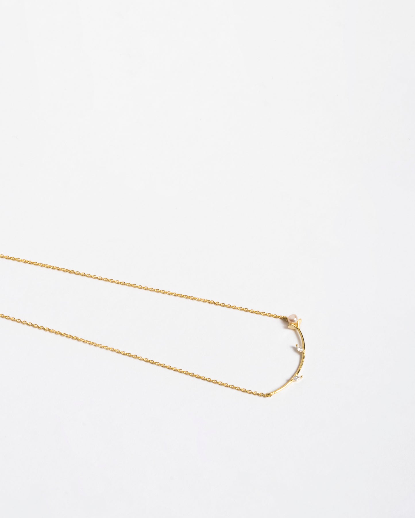 Dettaglio del design giapponese della collana Akoya Branch: particolare del ramoscello dorato, della perla naturale e dei punti luce in zircone."