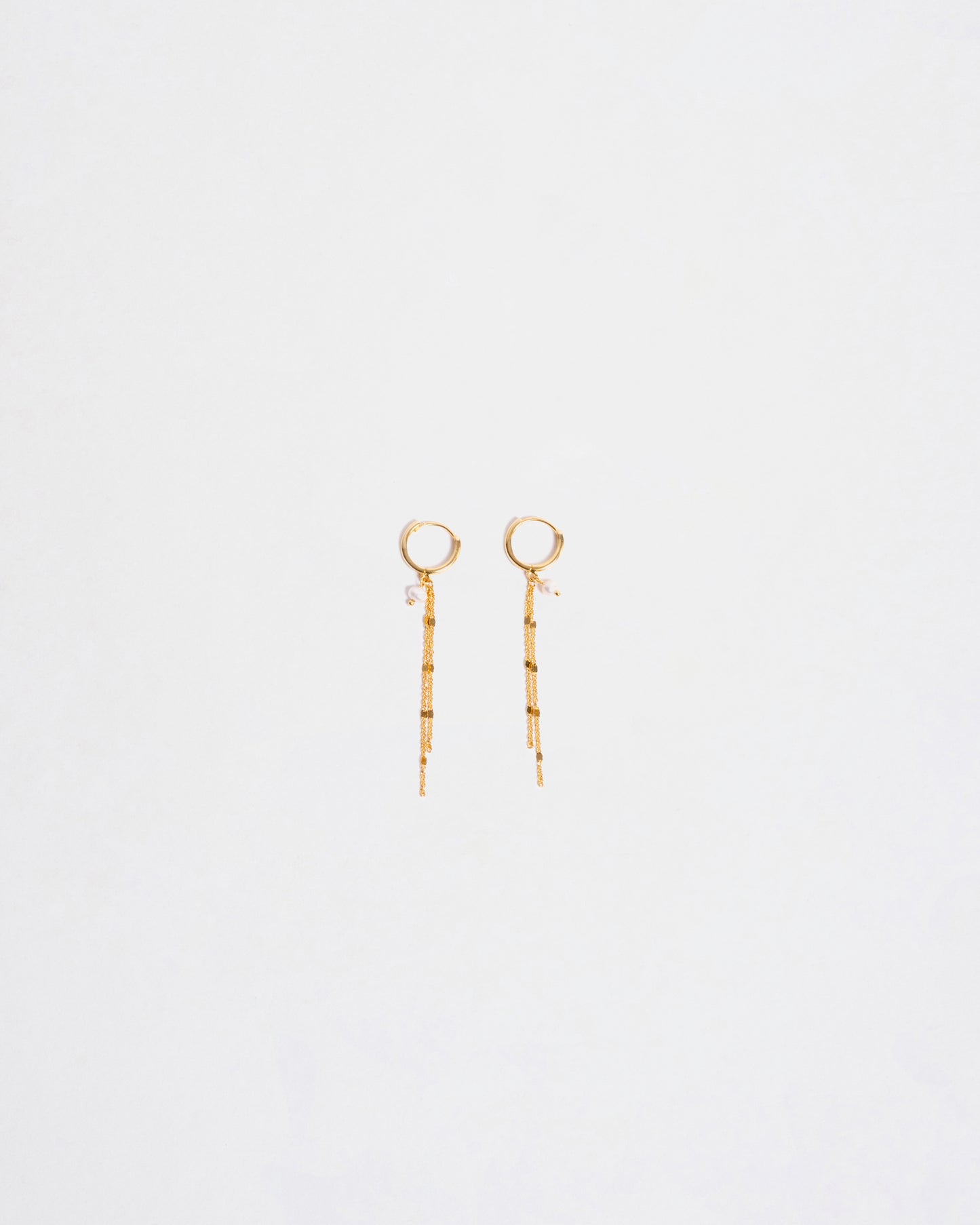 Un paio di orecchini pendenti placcati oro su argento 925 con catenine a cascata e perle, su sfondo bianco."