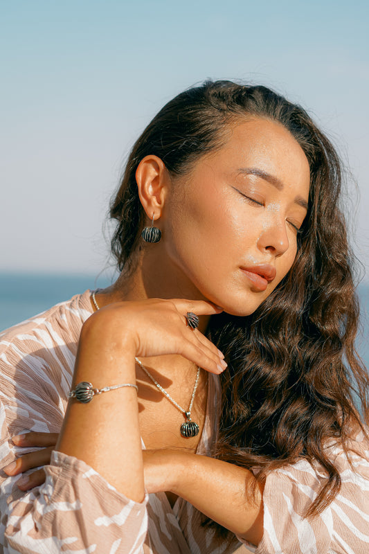 "Modella indossa la parure completa Guscio di Shali Éclat Gioielli: orecchini, collana, bracciale e anello in Argento 925 brunito. Un look materico e scultoreo ispirato all'Oasi di Siwa."