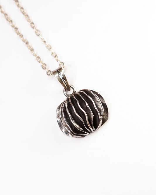 "Collana Guscio di Shali Éclat Gioielli: pendente lamellare in Argento 925 brunito. Design scultoreo e artigianale della Collezione Siwa ispirato alle rocce dell'Oasi."