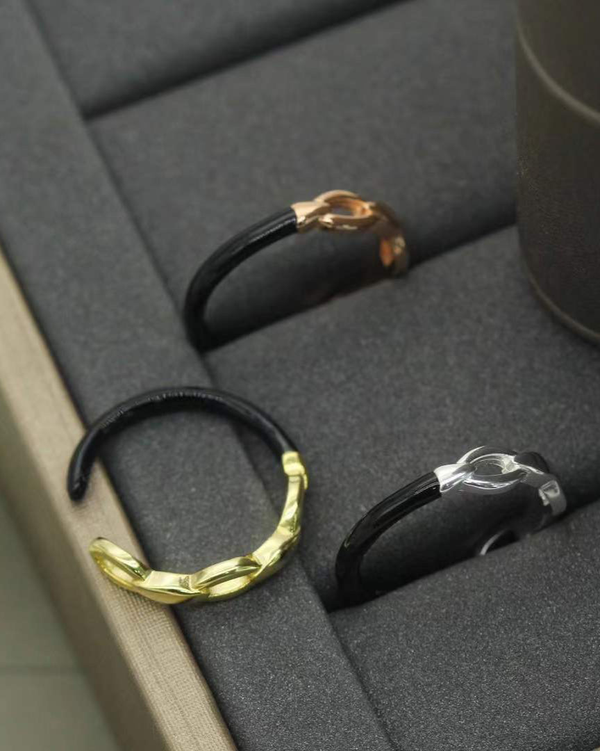 Open band ring made of 925 Sterling Silver with an intertwined link design. Polished silver color. Displayed on a dark surface 
