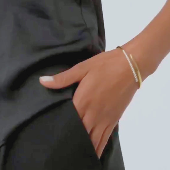 bracciale tennis bangle indossato con outfit nero elegante, riflessi di luce sugli zirconi e movimento fluido del design rigido.